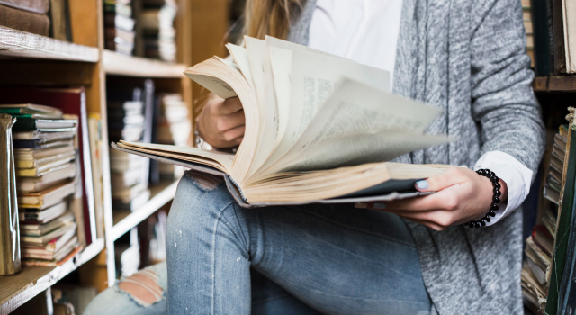 crop woman flipping book pages