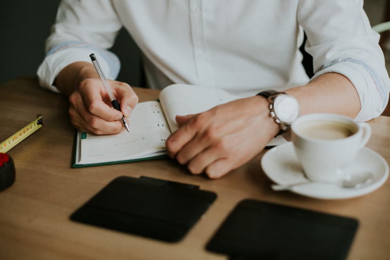 person taking notes notebook while working from home